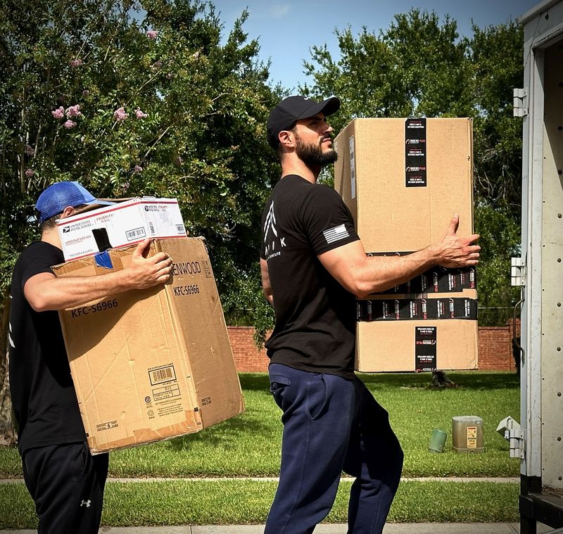 Two Heavy Lifters movers carrying boxes to a truck