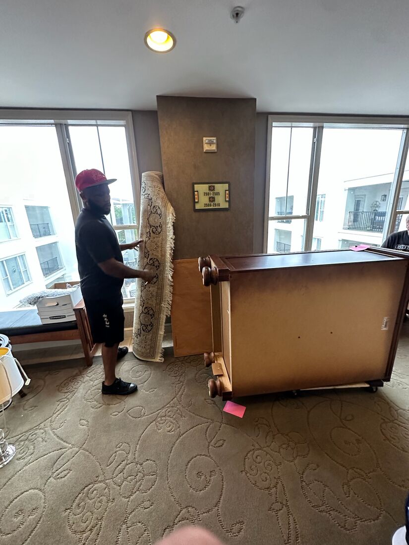 A Heavy Lifters mover carefully carrying a heavy dresser — movers serving Palm Beach Gardens, FL